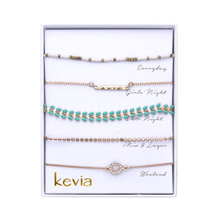 Gold bracelet set featuring turquoise leaf charms, white and gold seed beads, hammered bar, textured gold beads, and pavé circle charm.