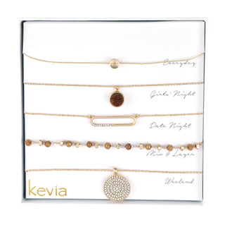 Five-piece gold necklace set with smoky quartz beads, druzy pendant, crystal bar link, and round crystal medallion, packaged in a gift box.