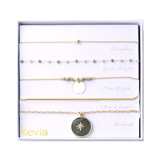 Five-piece gold necklace set with pearl bead accents, iridescent shell charm, herringbone chain, and coastal-inspired compass medallion pendant.
