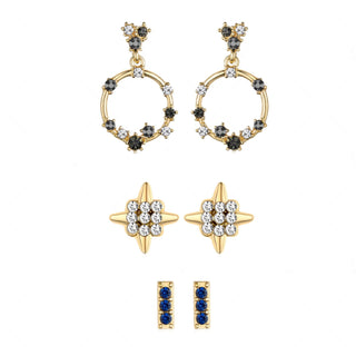 Three-pair gold-tone earring set featuring black and clear crystal floral hoops, gold starburst studs with pavé crystals, and sapphire-colored bar studs.