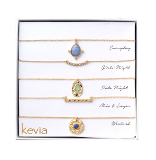 Five-piece gold necklace set with hammered medallion, gemstone pendants, and sleek gold bar accents, packaged in a gift box.
