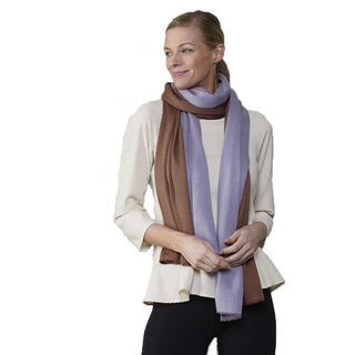 Woman wearing a long purple and mauve color block shawl draped around her neck over a cream blouse.