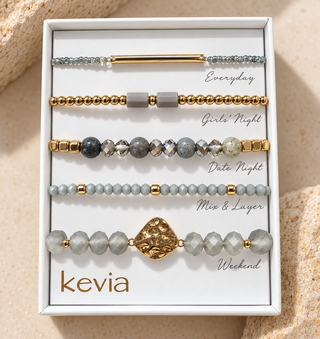 Five-piece grey and gold bracelet set with grey stone beads, gold beads, slim bar, and hammered gold centerpiece in an open Kevia box.