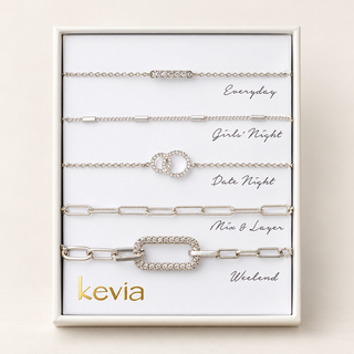 Five-piece silver bracelet set with crystal bar, rectangular stations, interlocking circles, elongated links, and pavé link in an open Kevia box.