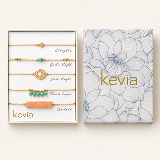 Five-piece gold bracelet set with coral and turquoise accents in an open box beside a floral Kevia lid.