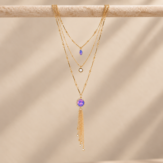 Gold layered necklace with opal and crystal charms and a long chain tassel pendant.