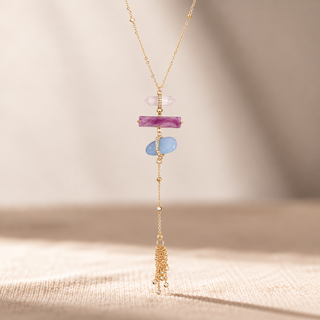 Gold necklace with pink and blue stone accents and a long chain tassel drop.