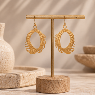 Gold oval feather hoop drop earrings with open centers and textured feather edges.