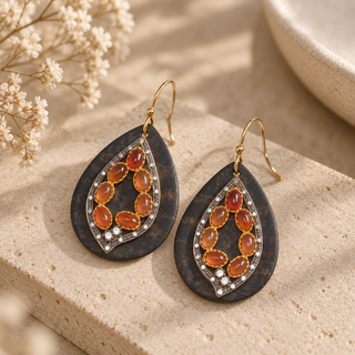 Dark teardrop earrings with orange oval stones and clear crystal accents.