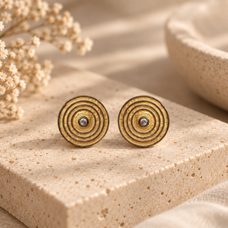 Gold concentric circle stud earrings with dark detailing and single crystal centers.