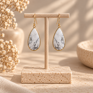 Gold drop earrings with white howlite teardrop stones and gray veining.
