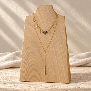 Gold layered necklace with an opal charm cluster and a long gold bar pendant.