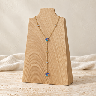 Gold Y-shaped necklace with blue opals and small crystal accents on a wooden display.