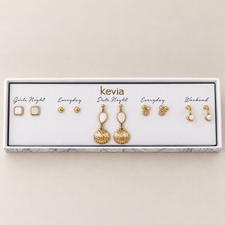 Five-pair gold earring set with white pearl and shell drops, square iridescent studs, gold balls, and crystal accents in an open Kevia box.