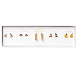 A Kevia jewelry gift set in a white rectangular box, featuring five pairs of earrings in different designs: watermelon,  cherry, grapes, strawberry and multi-colored hoop. The earrings are displayed on a white background inside the box.