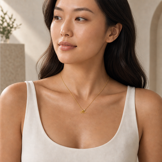 Model wearing gold chain necklace with a small bird pendant and a crystal accent.