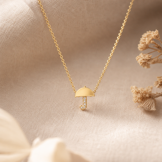 Gold chain necklace with an umbrella pendant and a crystal-accented handle.