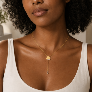 Model wearing gold Y-shaped necklace with a cloud charm and a long chain ending in a teardrop crystal pendant.