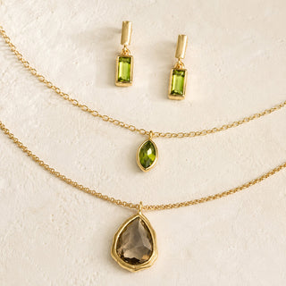 Three-piece gold mixed jewelry set with green drop earrings, green marquise pendant necklace, and smoky quartz teardrop pendant necklace.