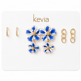 Three-pair earring set with blue-and-white floral drop earrings, crystal huggie hoops, and polished gold link drop earrings.