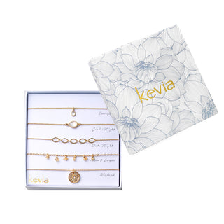 Five-piece gold necklace set with crystal teardrop pendant, mother-of-pearl oval station, open-link chain, golden chip-stone charms, and sunburst medallion, packaged in a gift box.