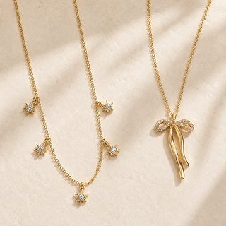 Gold Crystal Bow and Solitaire layered necklace set styled on warm stone