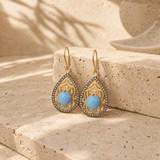 Gold filigree teardrop earrings with blue stones and dark crystal borders.