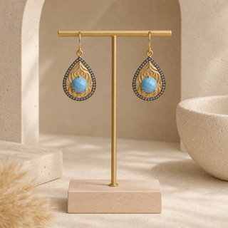 Gold filigree teardrop earrings with blue stones and dark crystal borders.