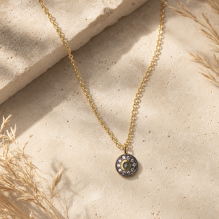 Gold chain necklace with a round smoky stone pendant and a dark crystal halo.