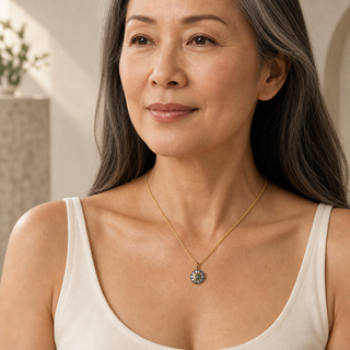 Model wearing gold chain necklace with a round pale green stone pendant and a dark crystal halo.