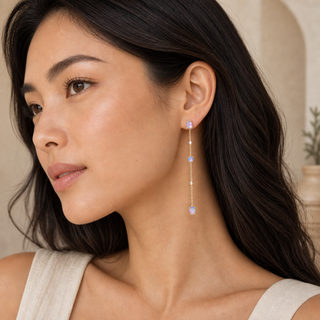 Model wearing long gold chain drop earrings with spaced opal and crystal accents.
