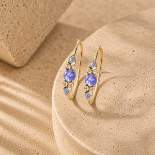Gold hoop earrings with blue opals and clear crystal accents along the front.