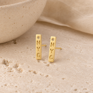 Gold NYC bar stud earrings with small crystal accents.