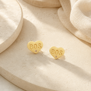 Gold heart stud earrings stamped BOS with small crystal accents.