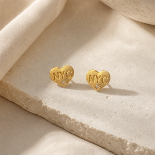 Gold heart stud earrings stamped NYC with small crystal accents.