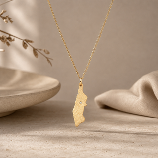 Gold chain necklace with a Manhattan-shaped pendant and a small crystal accent.