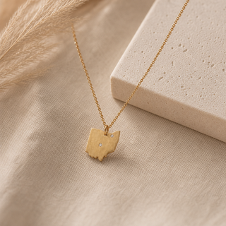 Gold chain necklace with a Ohio-shaped pendant and a small crystal accent.