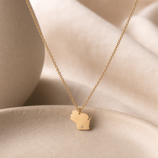 Gold chain necklace with a Wisconsin-shaped pendant and a small crystal accent.