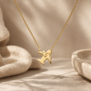 Gold chain necklace with an airplane pendant stamped ATL and small crystal accents.