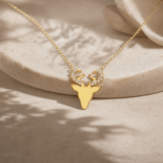 Gold chain necklace with an elk head pendant and crystal-accented antlers.