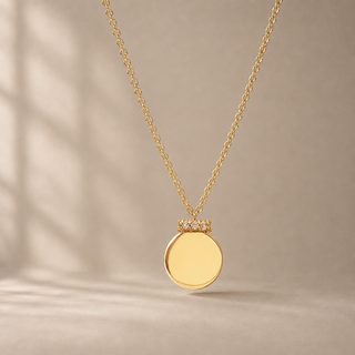 Gold chain necklace with a round ornament pendant and a crystal-accented top.