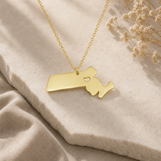 Gold chain necklace with a Massachusetts state pendant and a heart cutout.
