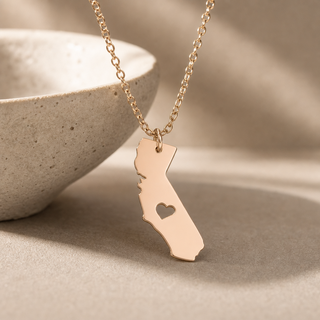 Rose gold chain necklace with a California state pendant and a heart cutout.