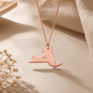 Rose gold chain necklace with a New York state pendant and a heart cutout.