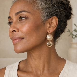 Model wearing gold double circle drop earrings with textured upper discs and hammered lower discs.