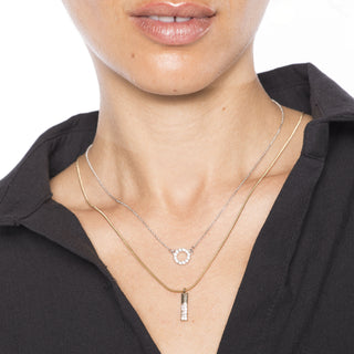 Layered gold and silver necklaces with diamond circle and vertical bar pendants worn on model.”
