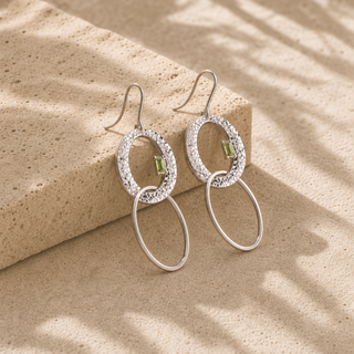 Silver oval drop earrings with hammered open oval tops, small green stones and thin oval drops.